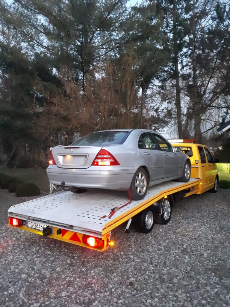 Laweta Berlin przewożąca uszkodzony samochód na ulicach miasta, szybka i profesjonalna pomoc drogowa. 🚗🔧