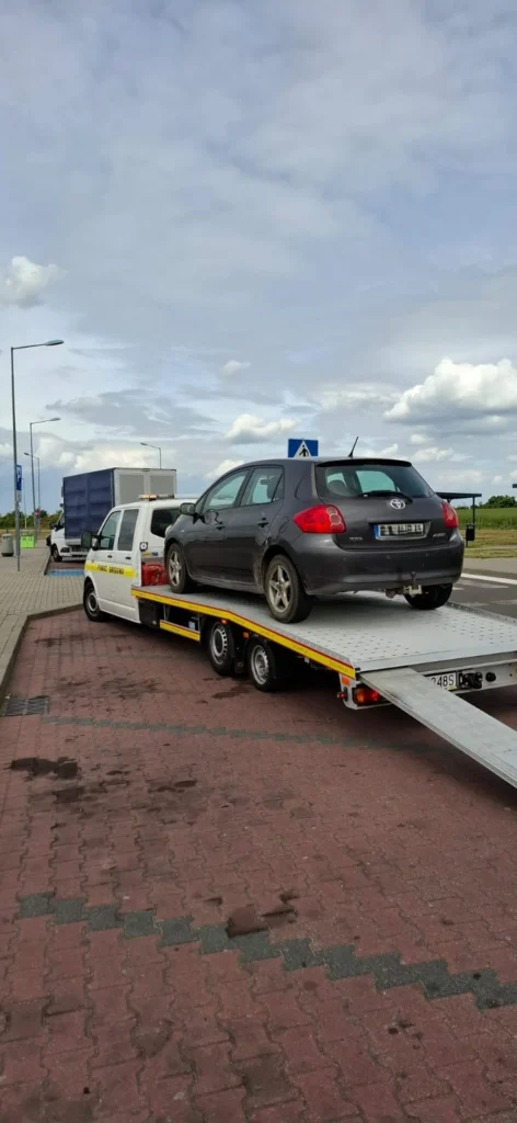 Samochód z otwartą maską na ulicy, a obok pracownik pomocy drogowej Berlin uruchamia pojazd po awarii akumulatora.